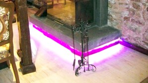 A room with a stone fireplace, a wooden bench, and a decorative metal stand. - Hotel Edirne Osmanli Evleri (Edirne)