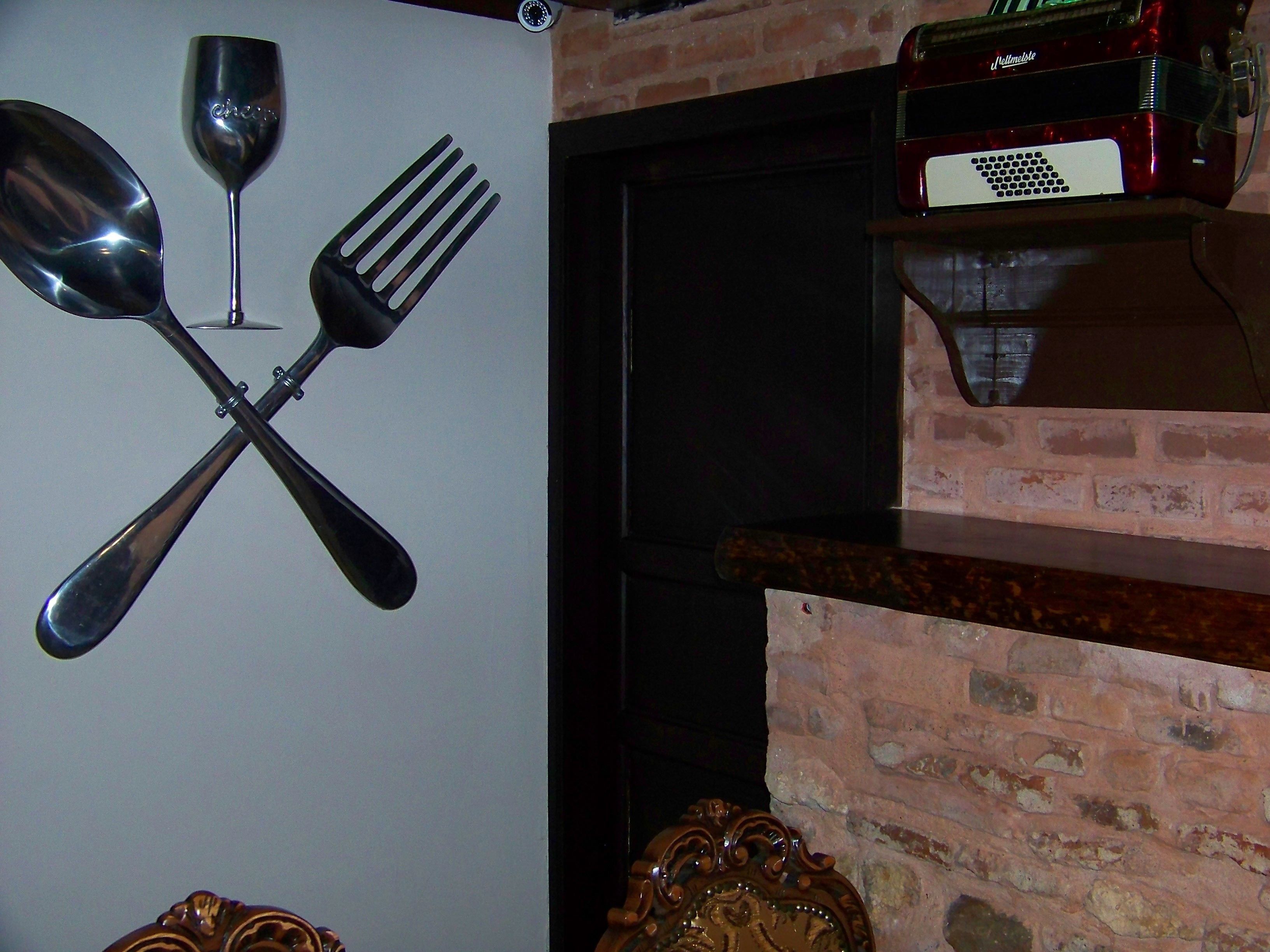 A wall-mounted set of utensils, a brick wall, and a shelf with a red appliance.