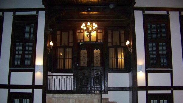 A traditional building with a wooden entrance, a staircase leading up to a door, and a decorative chandelier. - Hotel Edirne Osmanli Evleri (Edirne)