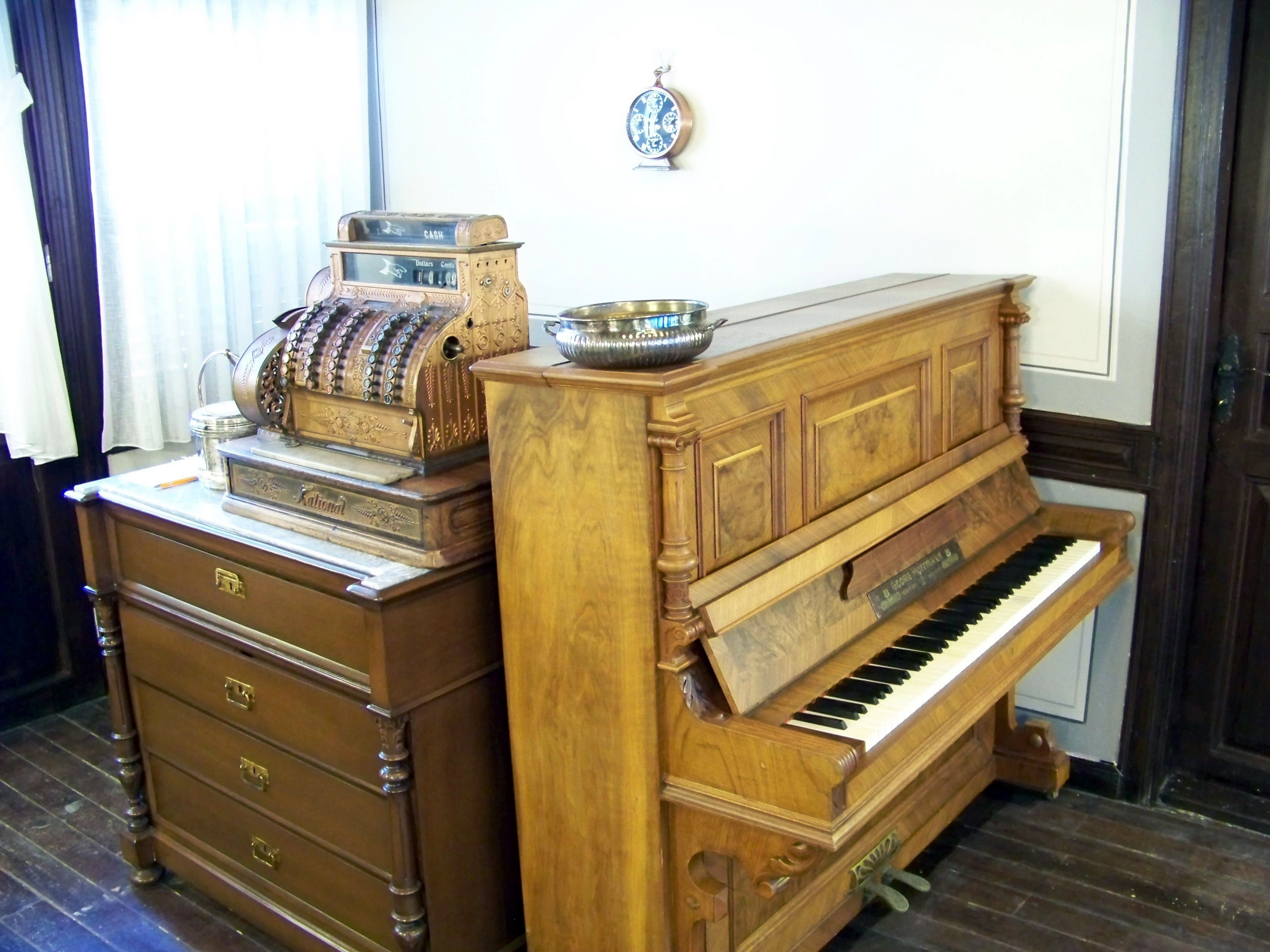 Un piano droit ancien, avec un placage en bois et une plaque métallique sur la façade.