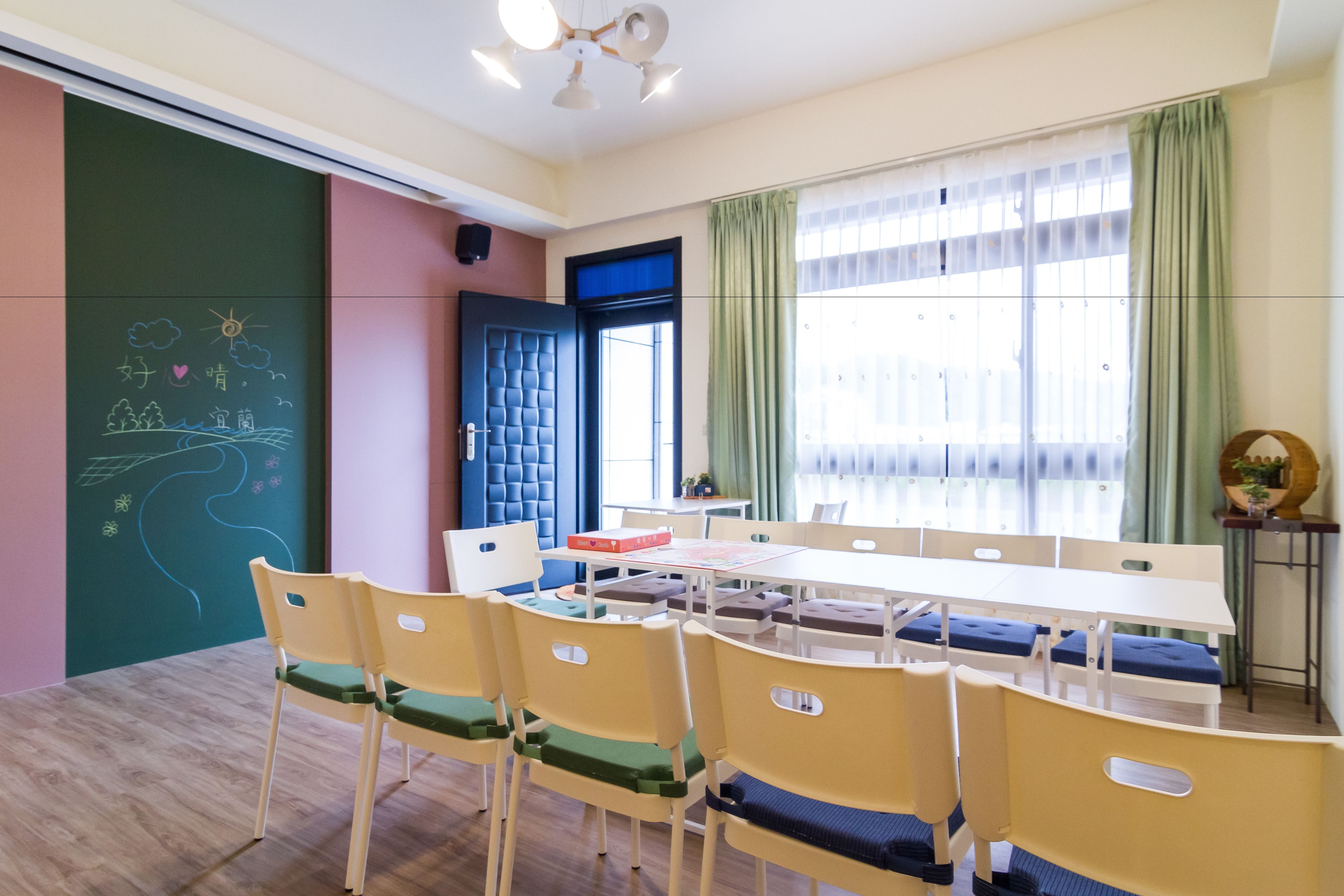 A conference room with a long table, chairs, and a large window with curtains.