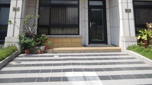 Un edificio de varios pisos con un estilo arquitectónico moderno, que presenta una entrada central con una puerta de madera y un área de recepción con azulejos.