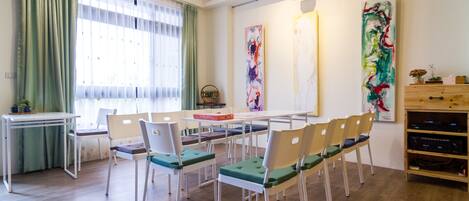 Une pièce comprenant une table à manger, des chaises, un petit bureau et des œuvres d’art accrochées aux murs.