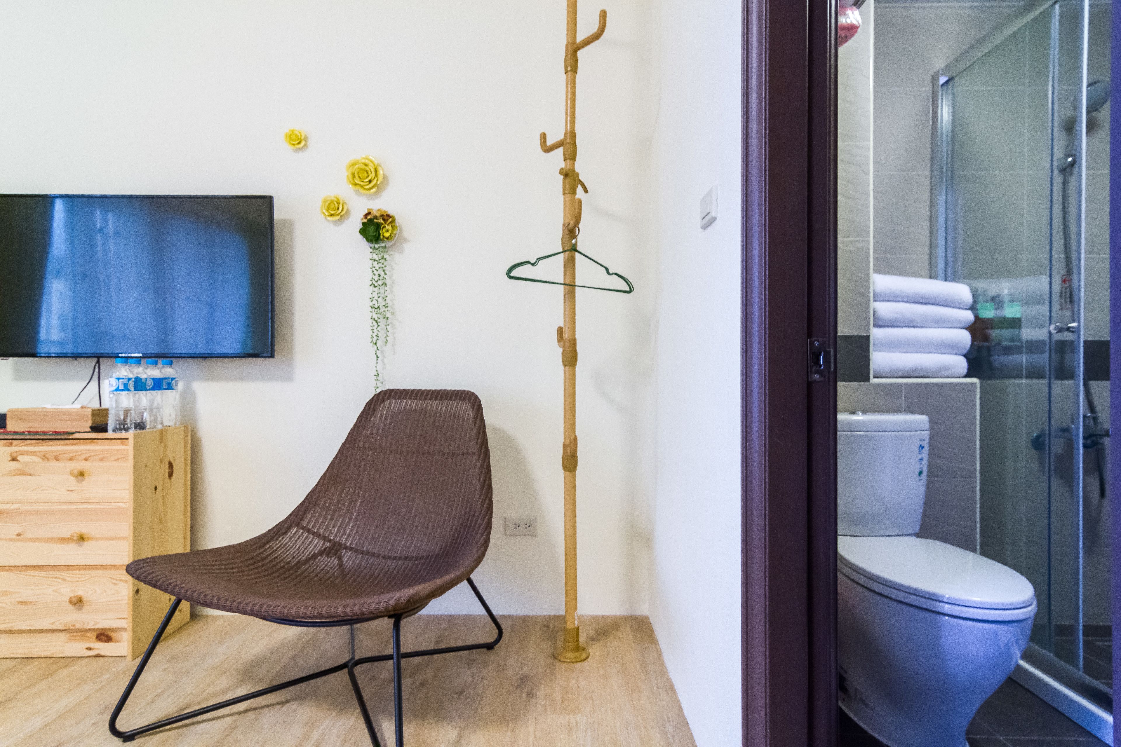 A modern bathroom with a shower, toilet, and a television on the wall.