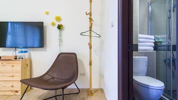 Un baño moderno con ducha, inodoro y televisión en la pared.
