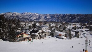 A snow-covered mountain town with buildings and a ski slope. - Marillen Hotel (Hakuba)