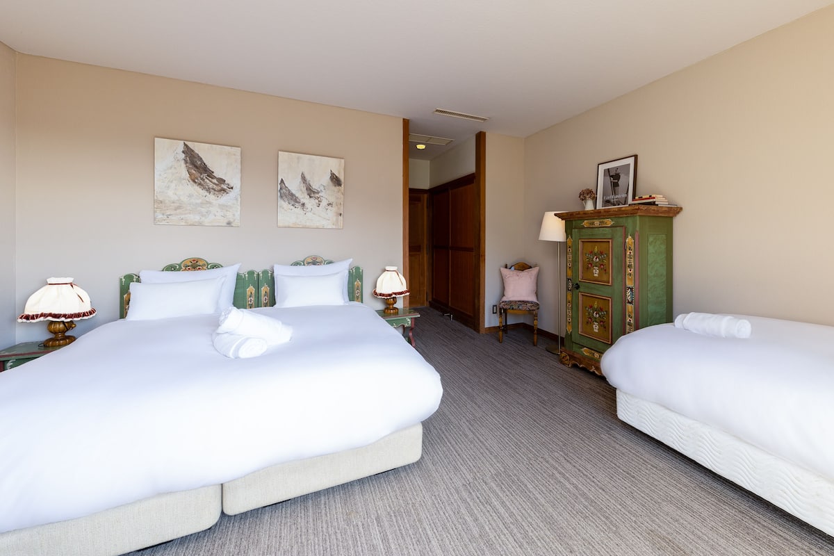 Habitación de hotel con dos camas, un armario verde y obras de arte en las paredes.
