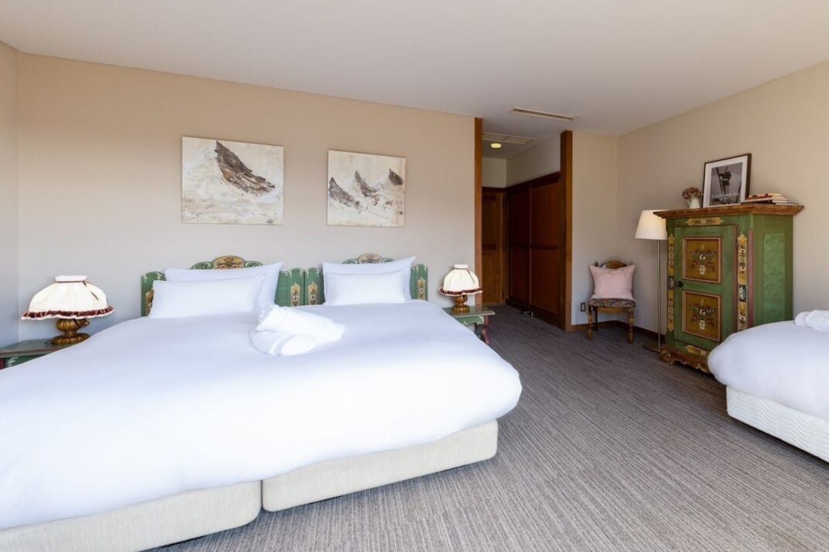 Habitación de hotel con dos camas, un armario de madera y obras de arte en las paredes.