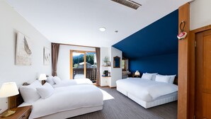 A hotel room with two beds, a wooden nightstand, a lamp, a window with a view of mountains, and a blue accent wall. - Marillen Hotel (Hakuba)