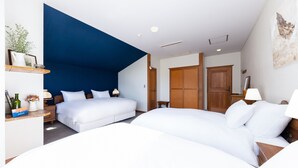 A hotel room with two beds, a blue accent wall, wooden furniture, and a painting on the wall. - Marillen Hotel (Hakuba)