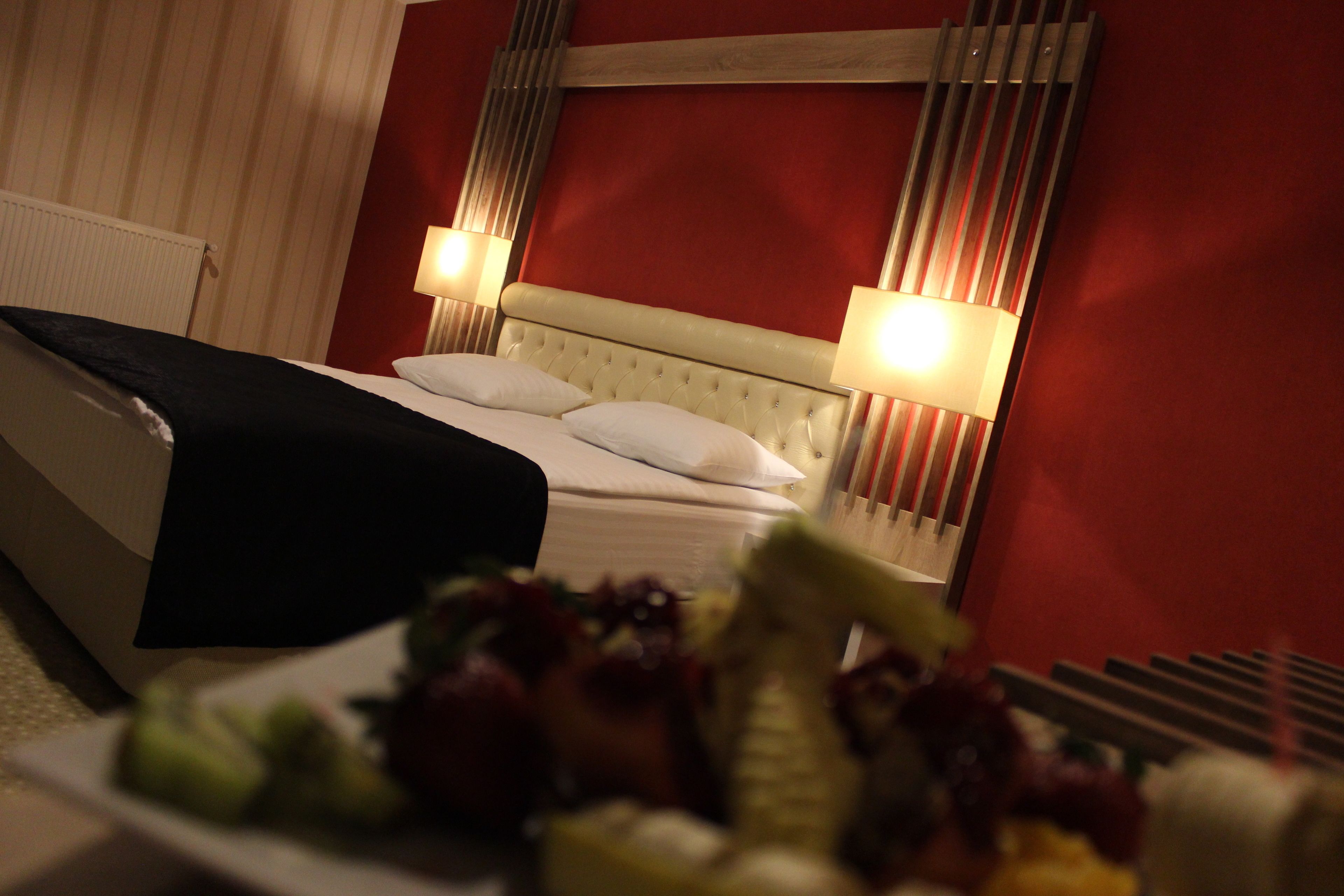 Una habitación de hotel con una cama, dos lámparas de noche y una cesta de frutas a un lado.