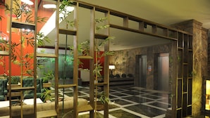 Um hall com chão xadrez, um balcão de recepção e um divisória de madeira com plantas.
