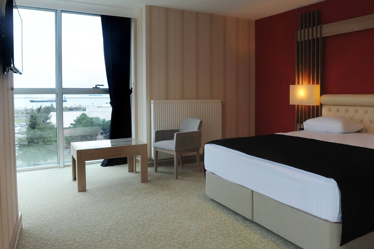 Une chambre d’hôtel avec un grand lit, une chaise, une table et une vue sur l’extérieur.
