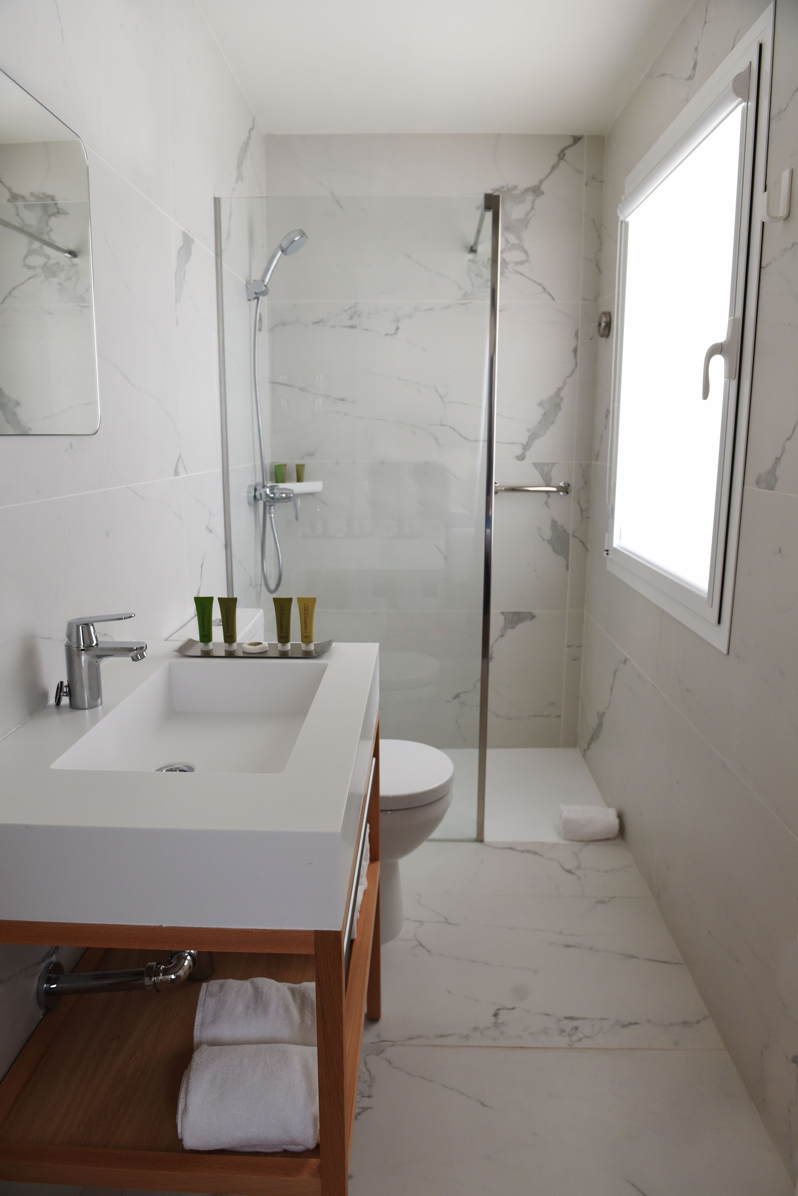 A modern bathroom with a large white sink, a glass-enclosed shower, and a toilet.