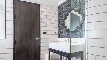 Un baño con puerta de madera oscura, paredes de azulejos blancos y cabina de ducha de vidrio.