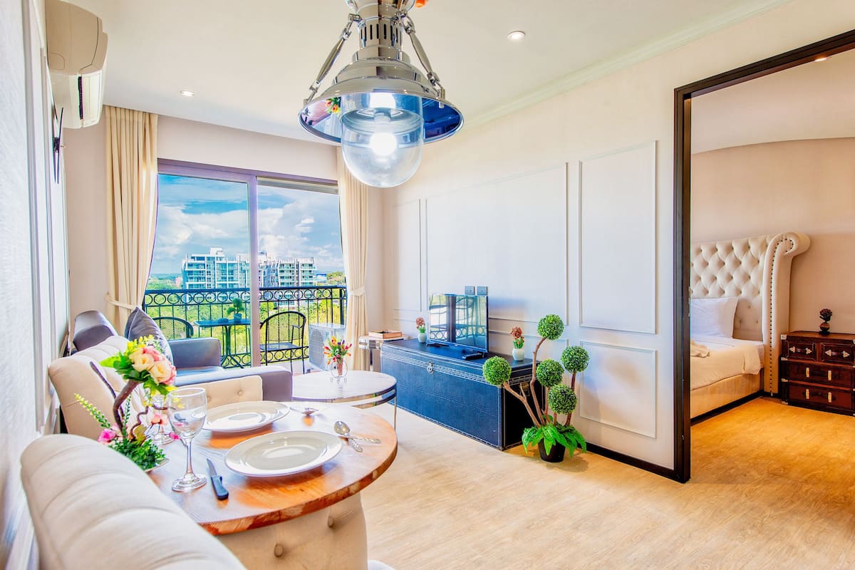 Una sala moderna con comedor, un ventanal con vistas a la ciudad, un sofá, una mesa de comedor y un dormitorio con una cama grande y cómoda.