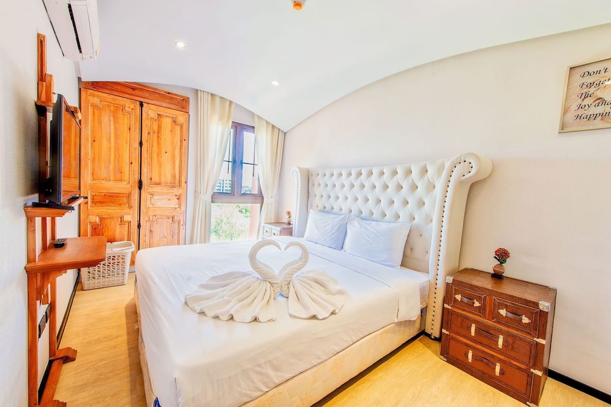 Un dormitorio con una cama grande, un armario de madera y un televisor.