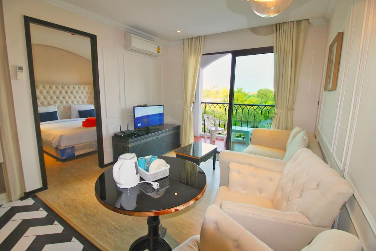Habitación de hotel con cama, televisión, sofá, una mesita y balcón con vistas.