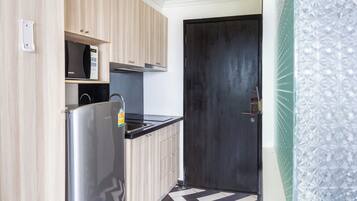 Una cocina moderna con armarios de madera clara, un refrigerador de acero inoxidable y una encimera negra.