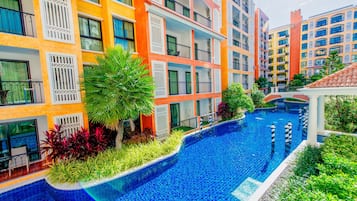 A multi-story hotel with balconies, a swimming pool, and lush landscaping.