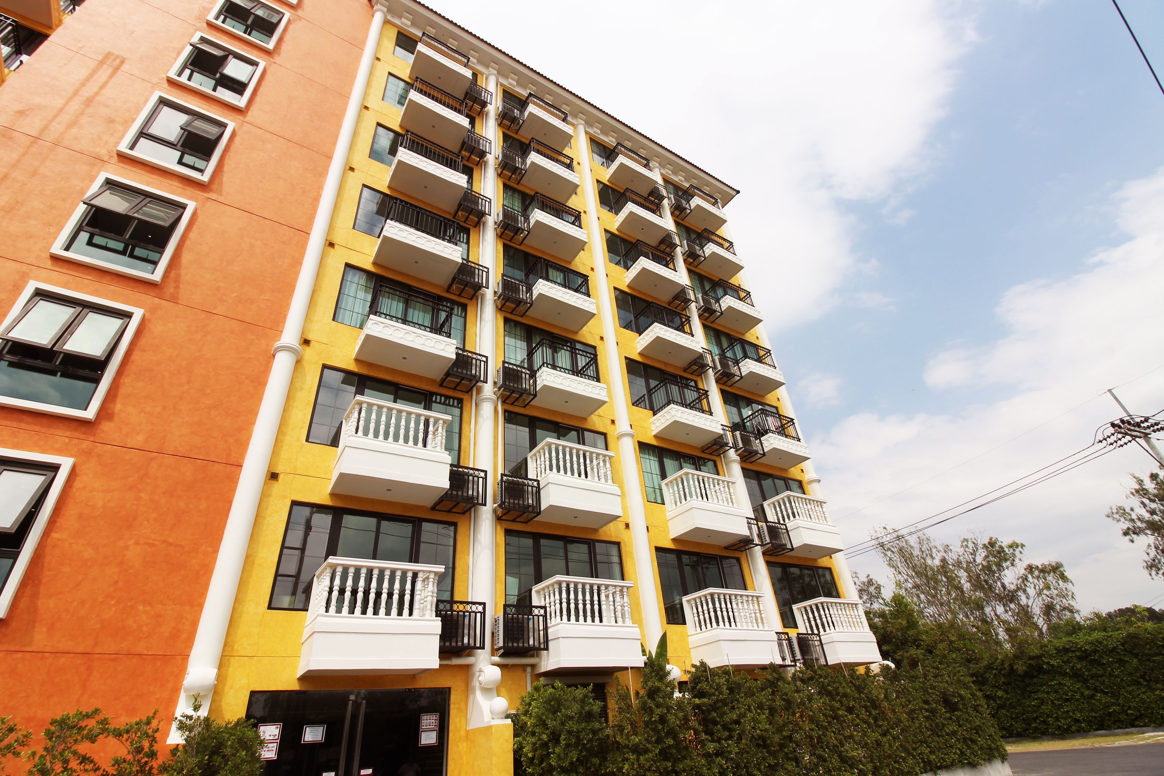 A multi-story building with balconies, large windows, and a yellow facade.