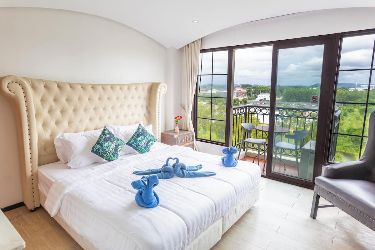Un dormitorio amplio con una cama grande, un balcón con mobiliario exterior y vistas a la ciudad.