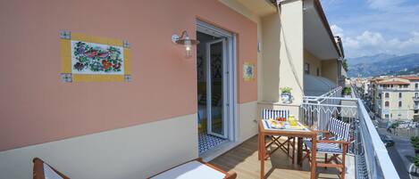 A balcony with two sun loungers, a table with chairs, and a decorative tile on the wall.