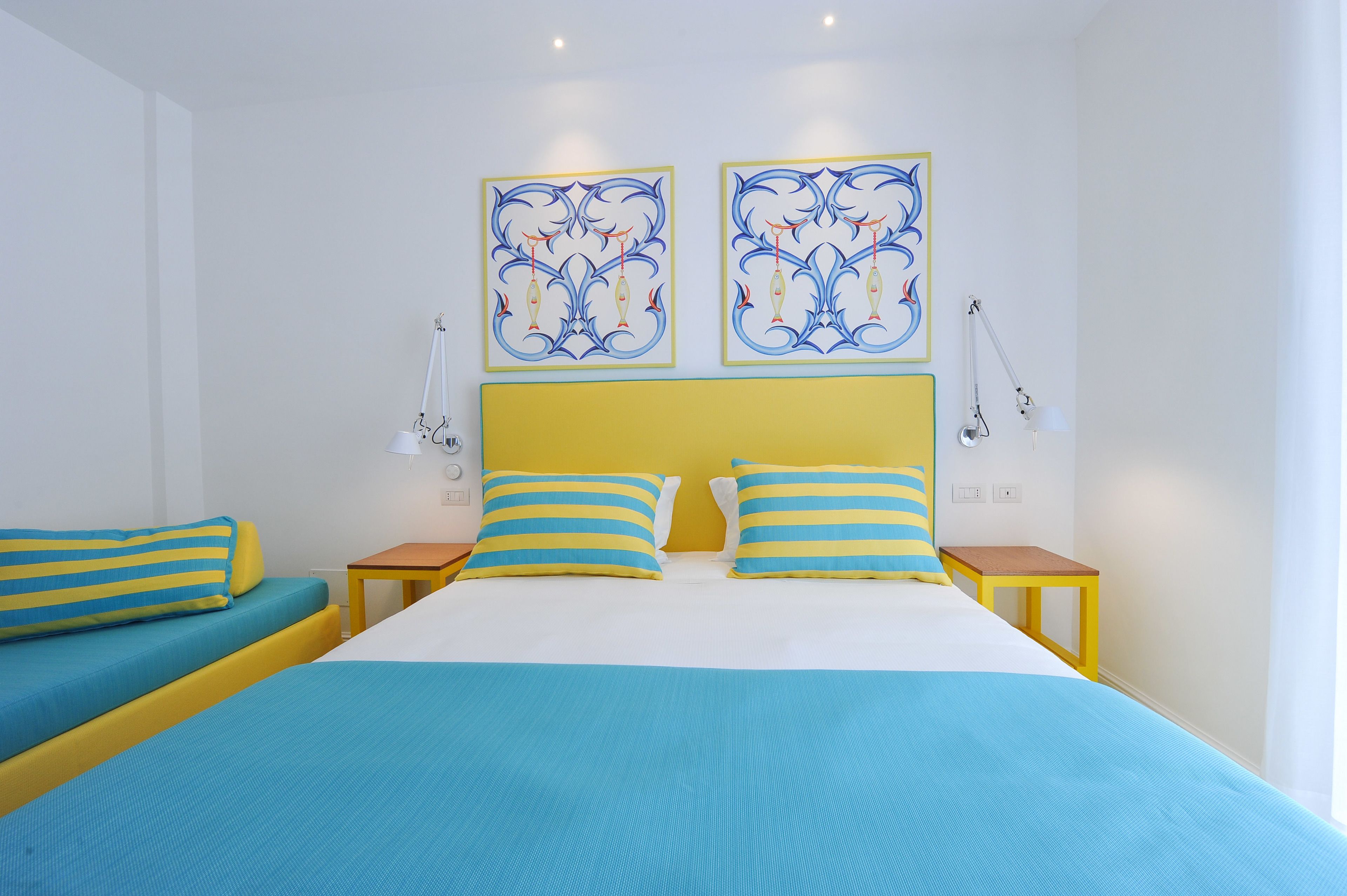 A bedroom with a bed, two bedside tables, and two wall-mounted lamps.
