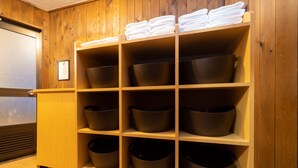 A wooden shelf unit with multiple black bowls and white towels. - Phoenix Hotel (Hakuba)