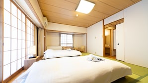 A hotel room with two beds, a wooden ceiling, a window with a view, a small table, and a door. - Phoenix Hotel (Hakuba)