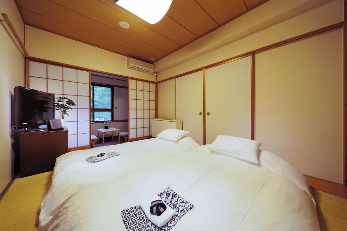 Un dormitorio japonés tradicional con cama, escritorio y televisor.