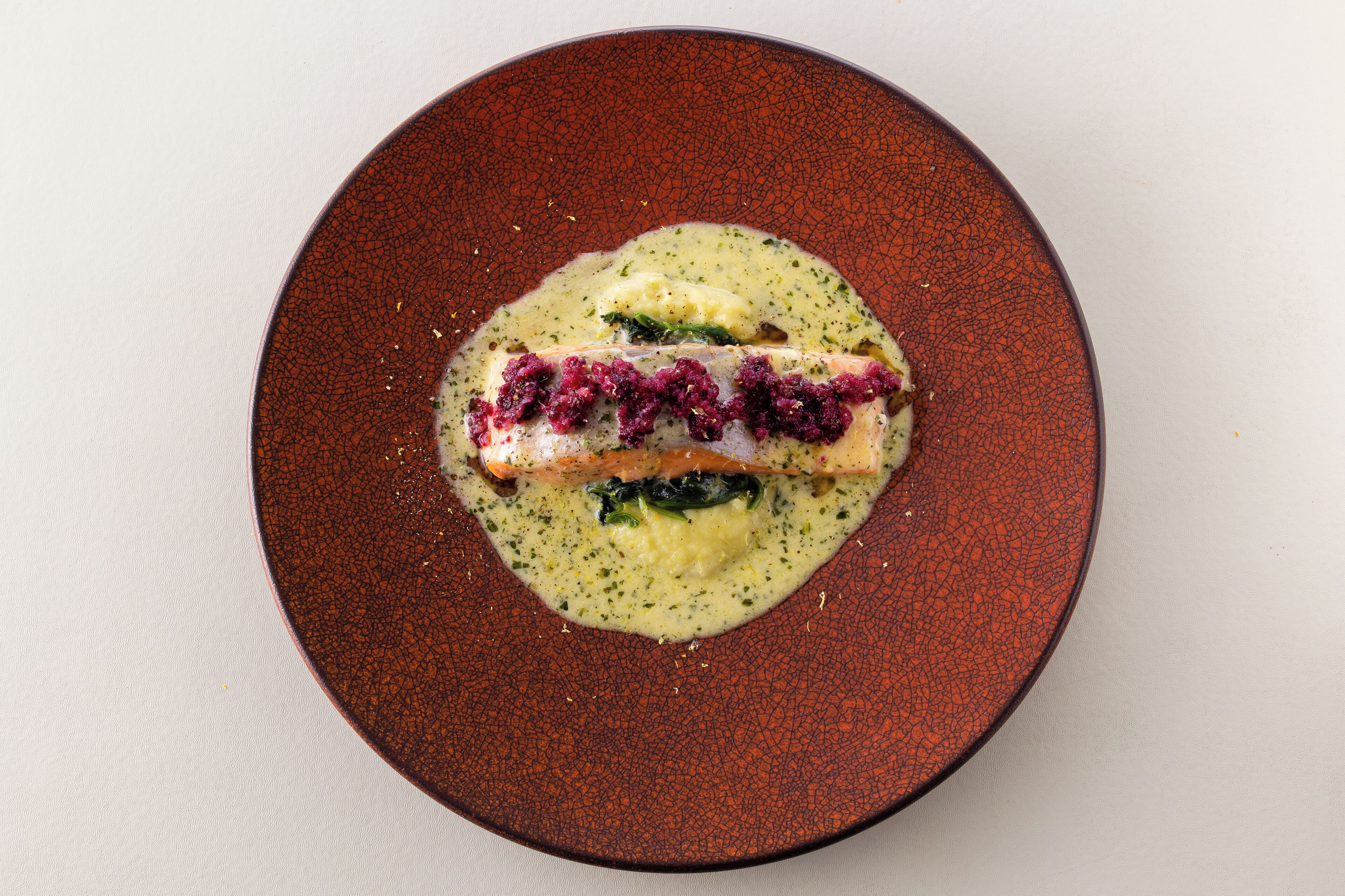 Une assiette contenant un filet de saumon, des épinards et une sauce crémeuse.
