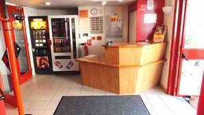 A reception area with a wooden counter, a vending machine, and a fire extinguisher. - Formul'Eco Maubeuge (Maubeuge)