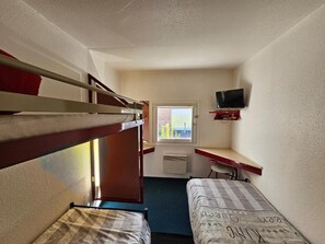 A dormitory room with bunk beds, a desk, a chair, a television, and a window with a view.
