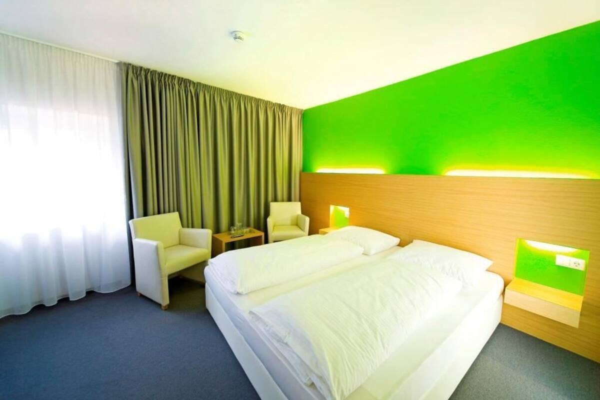 A hotel room with a large bed, two bedside tables, a chair, and a desk.