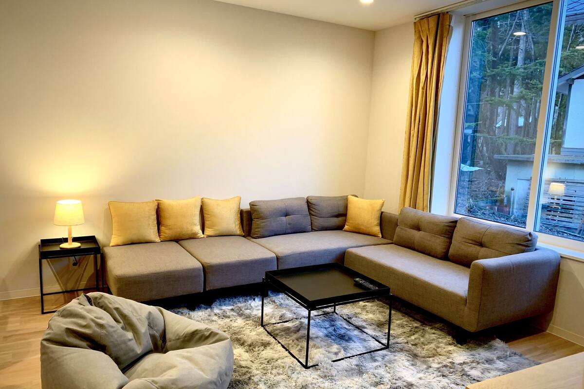 A modern living room with a sectional sofa, a small coffee table, and a bean bag chair.