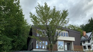 Ein modernes, zweistöckiges Haus mit einem großen Fenster und einem Baum davor.