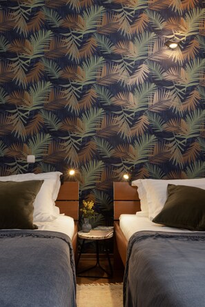 A hotel room with two beds, a small table with a vase, and a patterned wallpaper. - Luxe Dubrovnik Apartments (Dubrovnik)