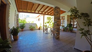 Un espacio de patio cubierto con suelo de baldosas, pilares de piedra y macetas con plantas.