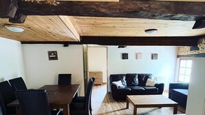 Un vaste espace de vie doté d’un plancher et d’un plafond en bois, d’une table à manger avec des chaises, d’un canapé et d’une table basse.