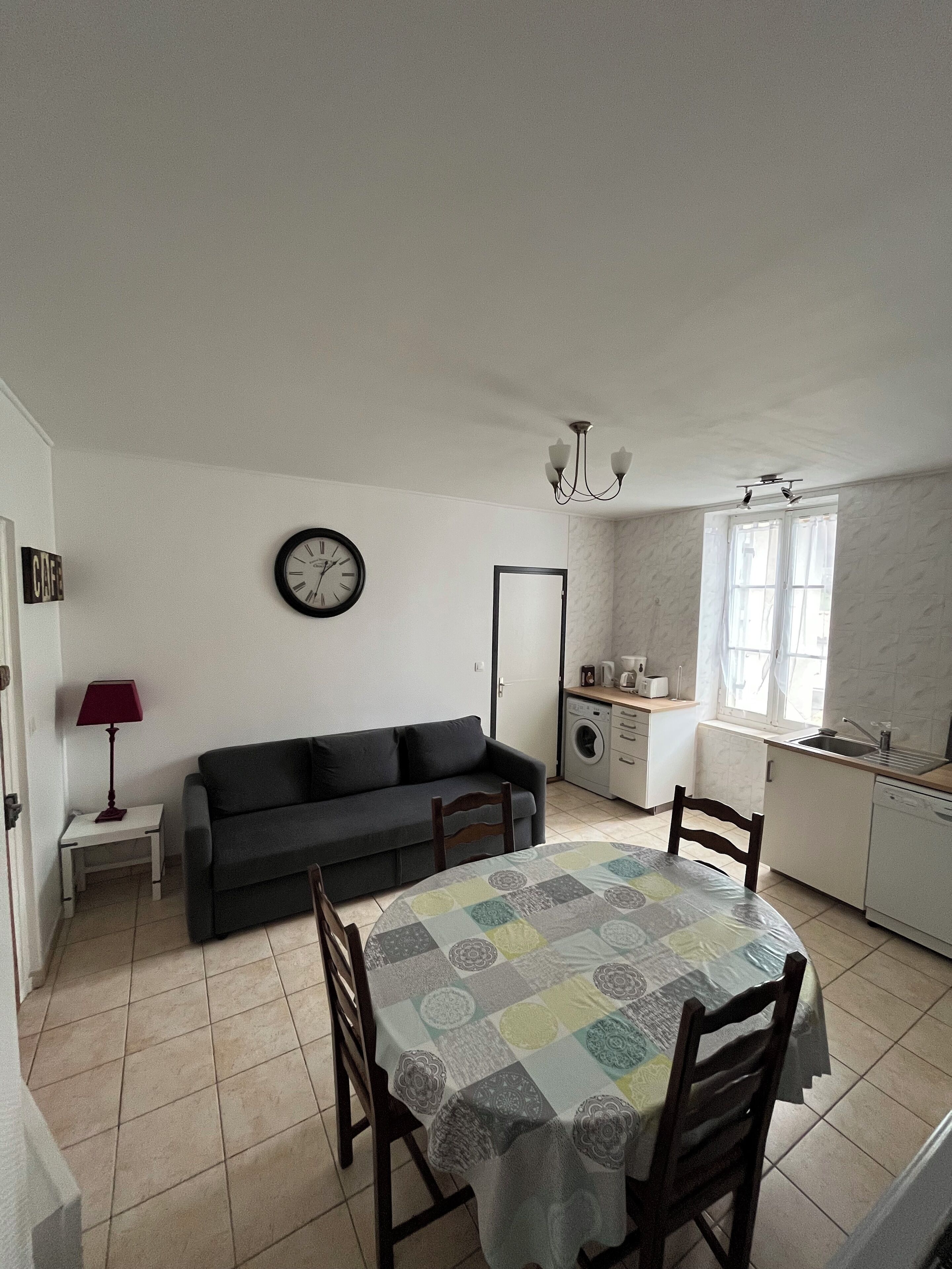 A compact living space with a dining table, sofa, and kitchenette.