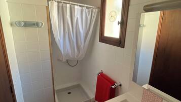 Une salle de bain équipée d’une douche, d’une baignoire, d’un lavabo et d’un miroir.