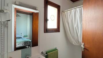 A bathroom with a wooden ceiling, a sink, a mirror, a window, and a shower curtain.