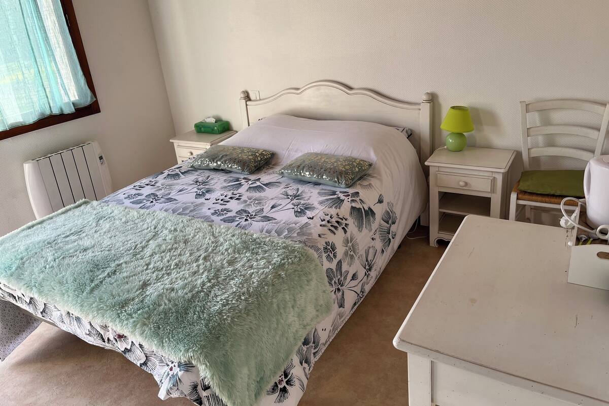 A neatly arranged bedroom with a bed, bedside tables, a lamp, and a chair.