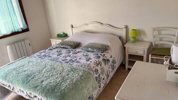 A neatly arranged bedroom with a bed, bedside tables, a lamp, and a chair.