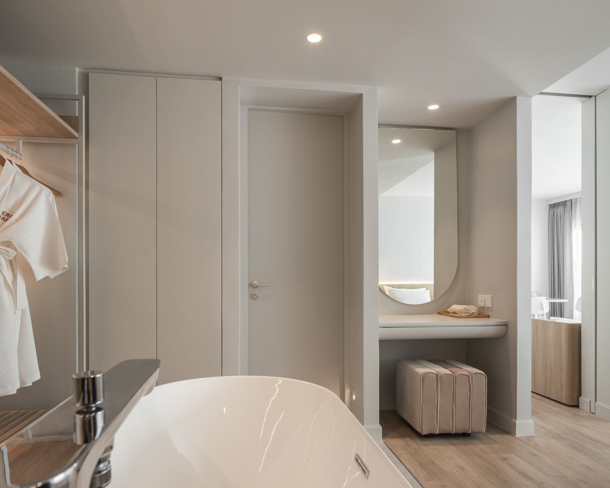 A modern bathroom with a large bathtub, a mirror, and a towel rack.