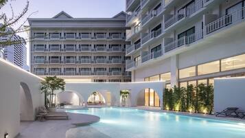 Una piscina al aire libre, sombrillas, sillones reclinables de piscina