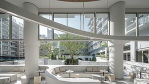 A modern interior with a curved seating area, large windows, and a view of surrounding buildings. - Terra Nara (Pattaya)