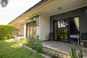Una casa moderna con un porche cubierto, puertas corredizas de vidrio y un pequeño jardín.
