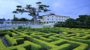 A maze garden with a large tree and a building in the background. - Haile Resort Ziway (Ziway)